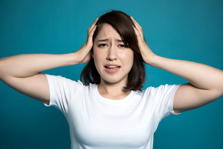 young woman holding her head in hands.