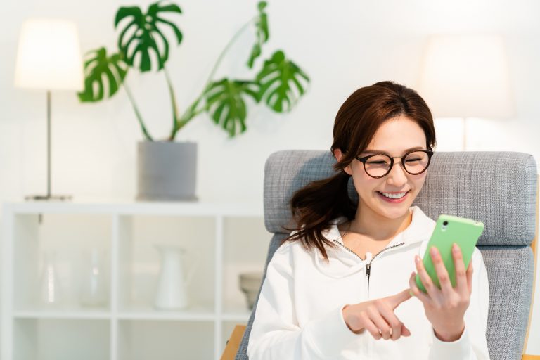 部屋でスマホを見る女性　