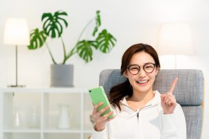 部屋でスマホを見る女性　