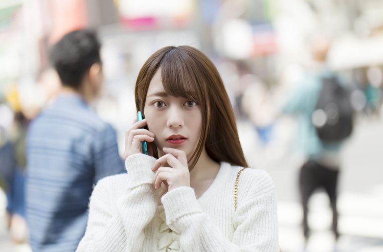 スマホで通話中に驚く女性