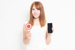 スマホとマルの判定プレートを持つ女性