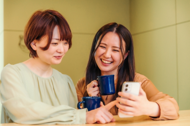 スマホを見ながら談笑する2人の女性