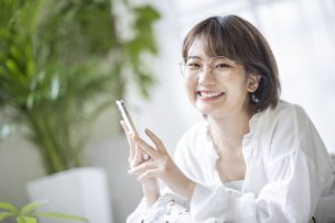 スマホを持ち笑顔の女性